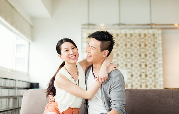 Young Chinese Couple Portrait of a young Chinese family in their Hong Kong apartment. chinese couple stock pictures, royalty-free photos & images