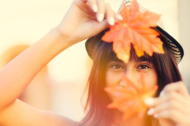 Young woman holding Autumn leafs in hands stock photo