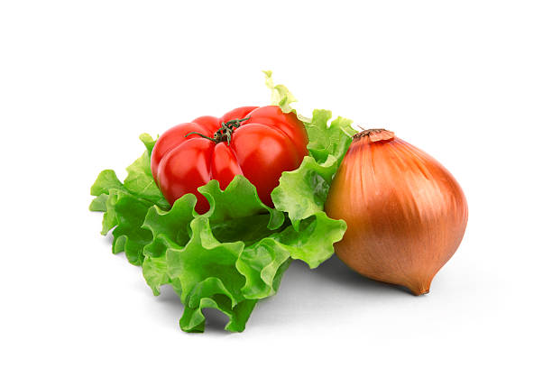 Tomato and onion lie on a salad leaf on a white background