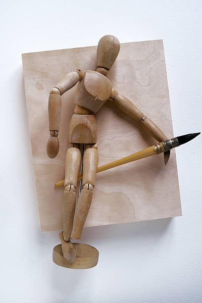 istock Wood Mannequin Holding Paintbrush With Empty Wood Panel 490857936