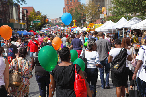 New York, NY, USA - September 28, 2014: View along the Atlantic Antic Street Fair which is held annually on Atlantic Avenue in the borough of Brooklyn, New York. Vendors sell art and food, sponsors display their products, and restaurants take to the sidewalk. The street fair attracts large multicultural crouds every autumn. Vendors give away colorful balloons to the visitors.
