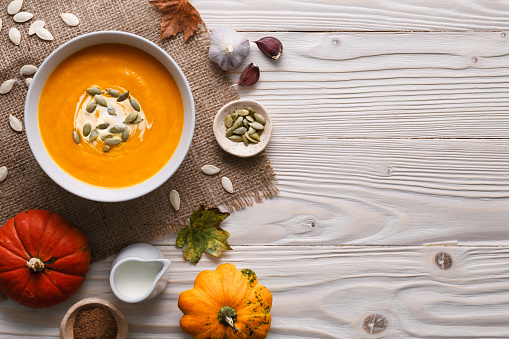 Traditional pumpkin soup with seeds and ingredients still life.