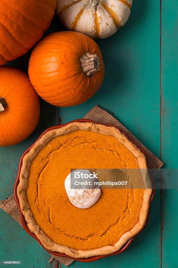 Pumpkin spice pie on rustic farm table A Thanksgiving day pumpkin spice pie with whipped cream and cinnamon topping. The holiday pie is photo is a aerial / looking down - vertical composition.  The pie is on a rustic blue/green farm table with copy space in the top right for text or design elements.  Please see my portfolio for other food and holiday related images.  Pumpkin Pie Stock Photo