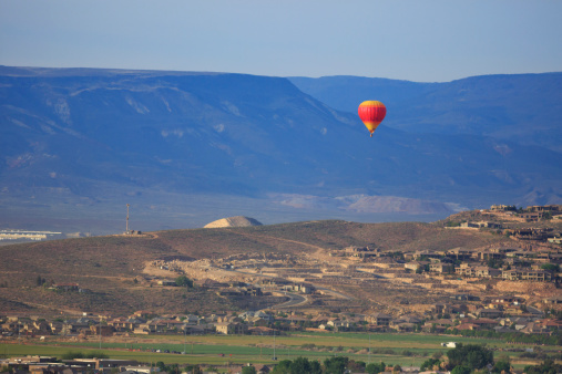 A hot air balloon drifts over houses and farms, and newly developing subdivisions on the outskirts of St. George, Utah
