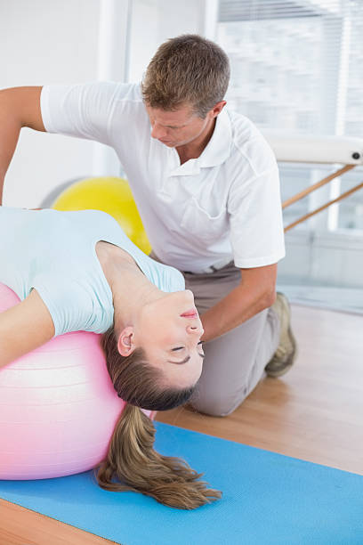 istock Trainer working with woman on exercise ball 490880184