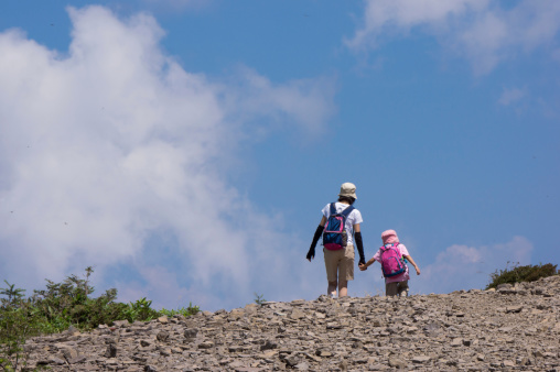 Parent and child walk the plateau which a cloud is close in.