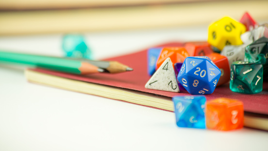 Close up of multicolored dice with Pencils on a red Notebook