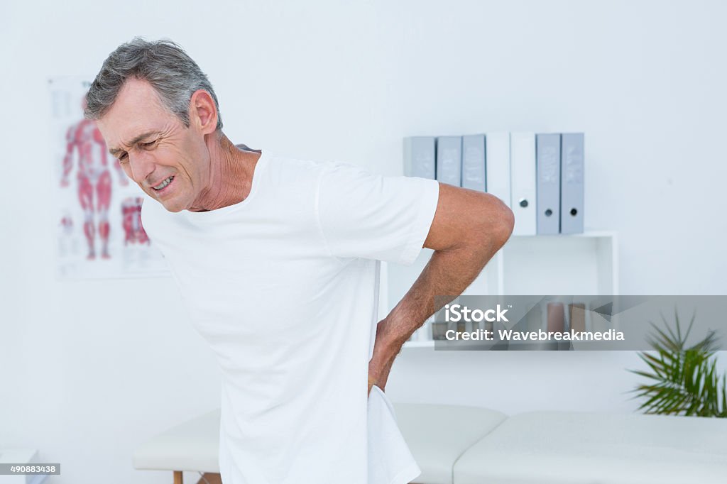 Suffering patient touching his back Suffering patient touching his back in medical office Backache Stock Photo