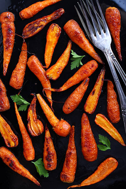 istock Young baked carrots on a black background 490883564