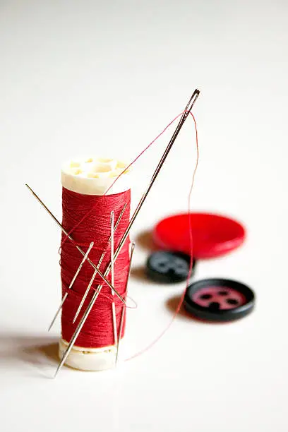 Red thread full of needles and sewing items