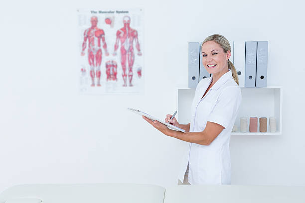 istock Doctor looking at camera and writing on clipboard 490884302