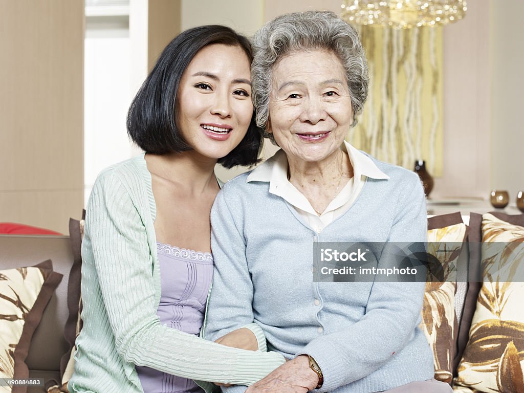 mother and adult daughter asian mother and adult daughter sitting on couch smiling. Mother Stock Photo