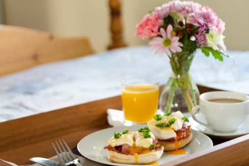 Eggs Benedict on breakfast tray on bed