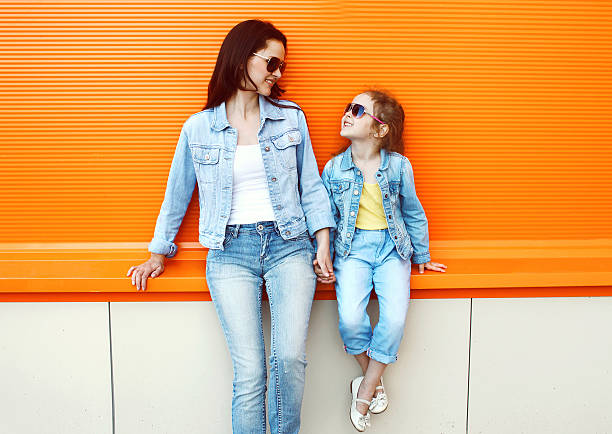 счастливая мать и ребенок, одетый в одежду в городе джинсы - fun mother sunglasses family стоковые фото и изображения