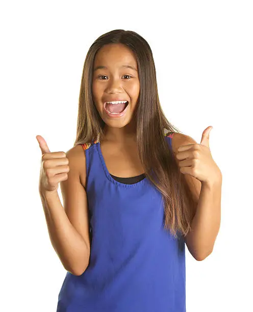 An eleven year old Filipino girl on a white background giving thumbs up.  She has an excited expression.