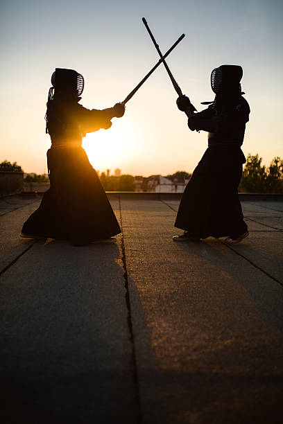 Kendo exercising Two persons exercising traditional Japanese martial art Kendo on the roof. Sunset kendo stock pictures, royalty-free photos & images
