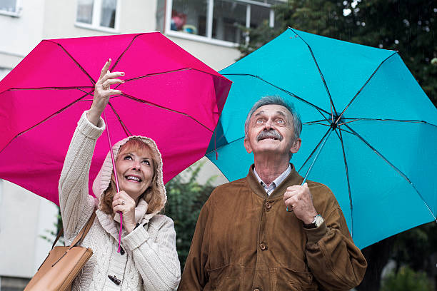 chuva começa a cair - umbrella senior adult couple autumn imagens e fotografias de stock