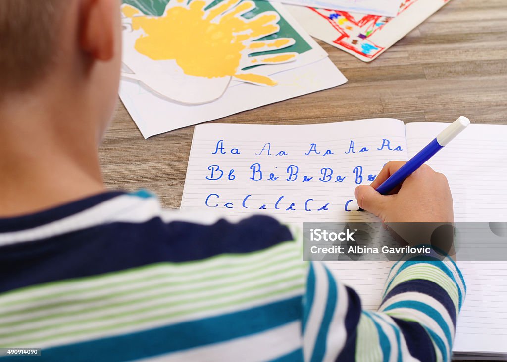 School Boy Writing on Paper  the alphabet with Pencil . School Boy Writing on Paper writing the alphabet with Pencil . Kid, homework, education concept Child Stock Photo