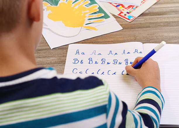 School Boy Writing on Paper  the alphabet with Pencil . stock photo