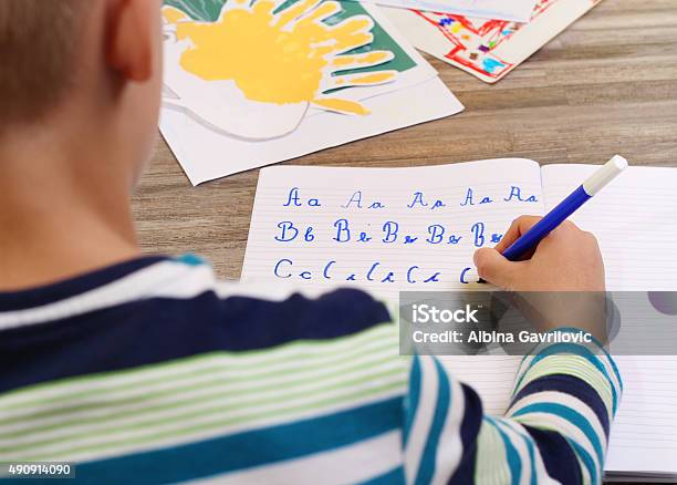 School Boy Writing On Paper The Alphabet With Pencil Stock Photo - Download Image Now