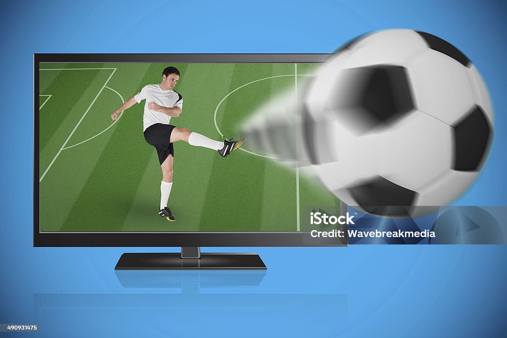Football player in white kicking ball out of tv Football player in white kicking ball out of tv against blue background with vignette 30-34 Years Stock Photo