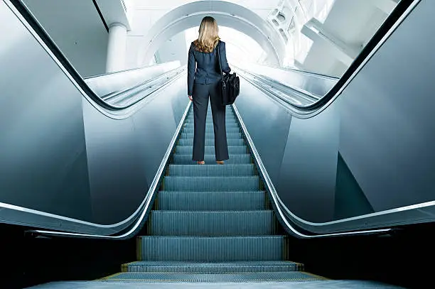 Photo of Businesswoman Riding Up An Escalator