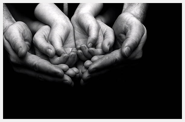 istock Adults hands holding kid hands on black background. 490934838
