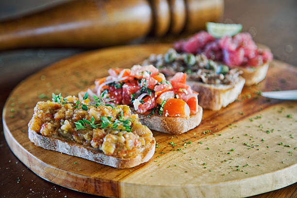 Bruschetta Mix Bruschetta served on a french baguette with eggplant paste, tomatoes, chicken paste and minced raw tuna crostini stock pictures, royalty-free photos & images