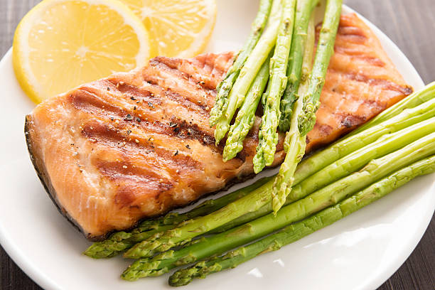 Grilled salmon with lemon, asparagus on the wooden background