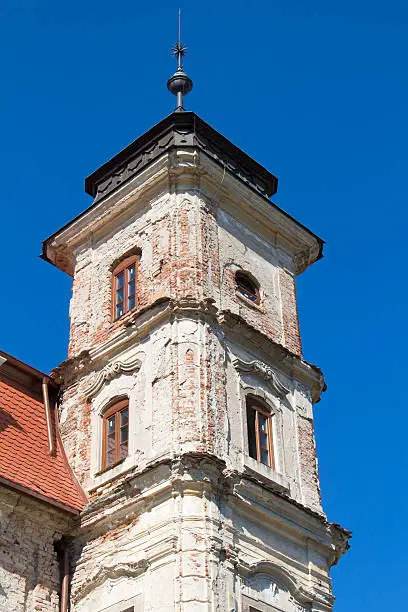 Not renewed as yet, tower of an old manor-house in Bernolakovo, Slovakia. New orange roof. Bright blue sky.
