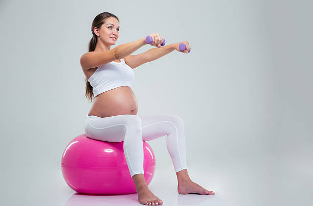 Woman doing exercises with dumbbells on a fitness ball stock photo