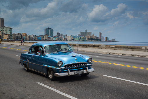 Havana, Cuba - September 28, 2015: Classic american car drive  on Malecon sea front promenade in Havana,Cuba. Classic American cars are typical landmark and tourist attraction for whole Cuban island.