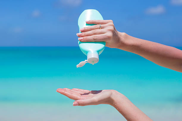 istock Woman hands putting sunscreen from a suncream bottle 490987593