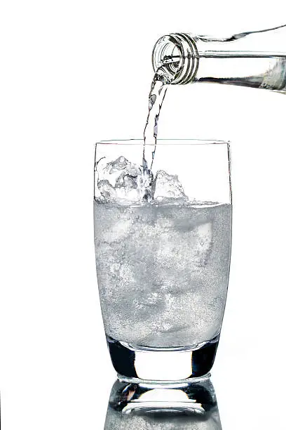 A soda water poured in a glass with ice.