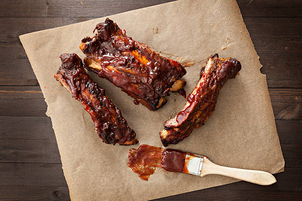 Barbecued Ribs A close up shot of several barbecued ribs and a sauce brush. barbeque sauce photos stock pictures, royalty-free photos & images