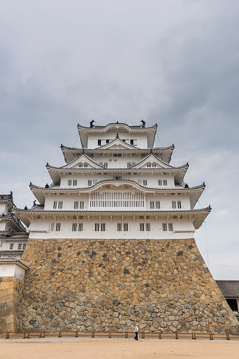 Himeji, Japan - August 12, 2015: The main tower of Himeji Castle, one of Japan's UNESCO world heritage sites with a tourist in front for scale