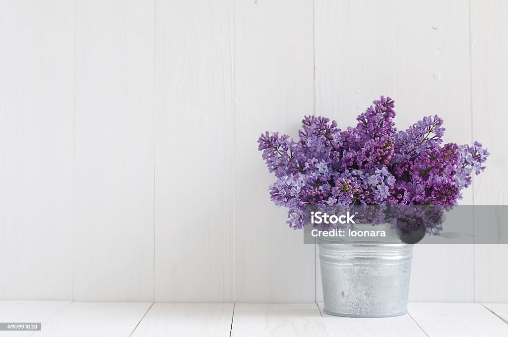 flowers of lilac Bouquet of beautiful spring flowers of lilac in a vase on a white vintage wooden board, home decor in a rustic style Arrangement Stock Photo