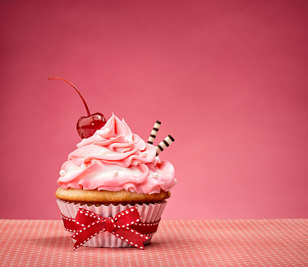 magdalena con glaseado con madera de cerezo rosa en la parte superior - ribbon nobody cupcake celebration fotografías e imágenes de stock