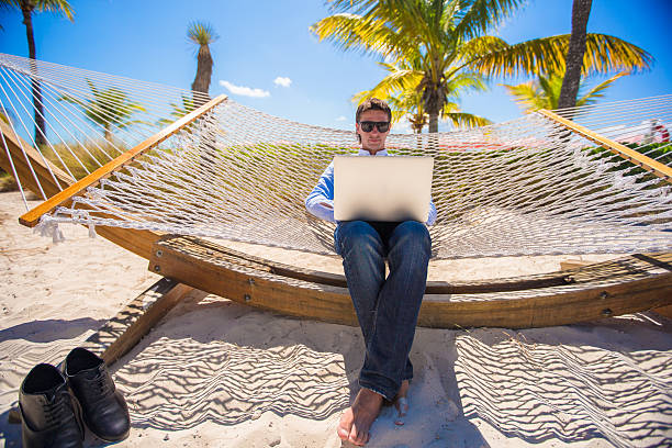 istock Businessman sitting in hammock using laptop during summer vacation 490992075