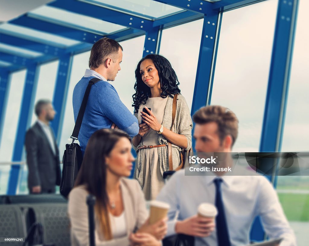 At the airport lounge People waiting for a flight at the airport lounge. Focus on the two people talking. 30-34 Years Stock Photo