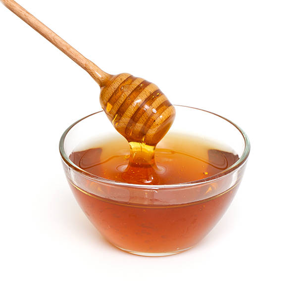 istock Honey dripping from a wooden dipper on white background 490994767