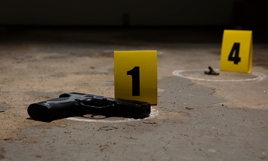 Crime scene with two evidence markers marking a gun and bullet casings