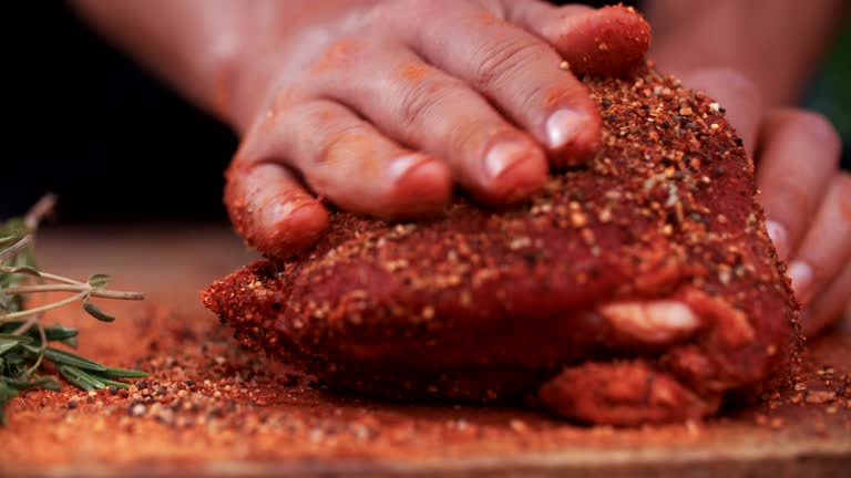 Seasoning of herbs and spices being rubbed into pork