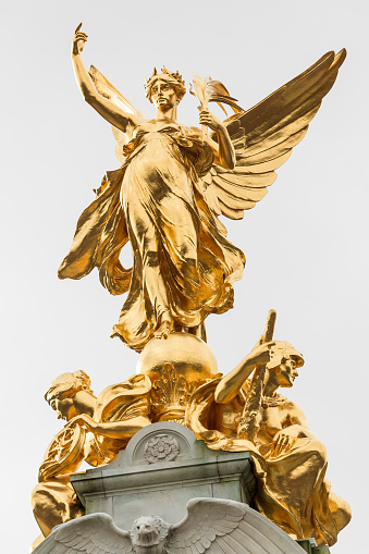 The golden angel with two seated figures on top of the Victoria Memorial in front of Buckingham Palace, London, UK