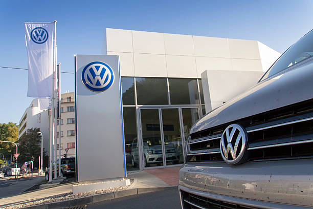 Car with Volkswagen logo in front of dealership building stock photo