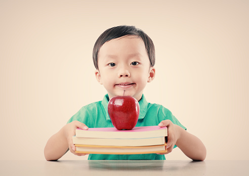 Child holding books and apple 