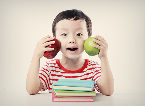 Child holding books and apple 