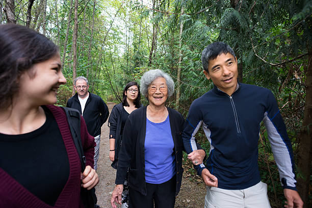 aktive senior asiatische frau zu fuß im wald wandern mit der familie - wildnisgebiets name stock-fotos und bilder