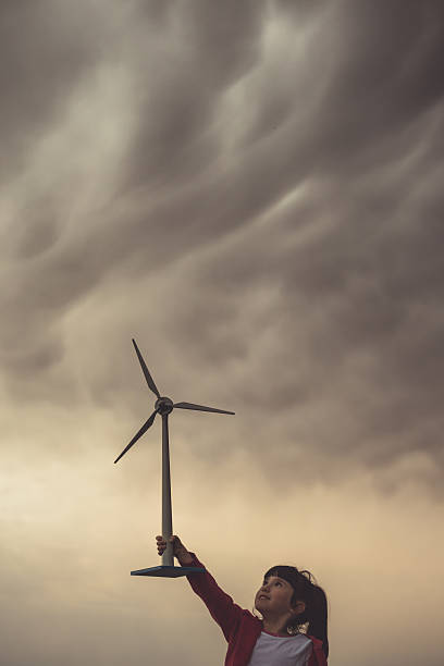 Child with a small wind turbine, at cloudy sunset (ecological symbol).