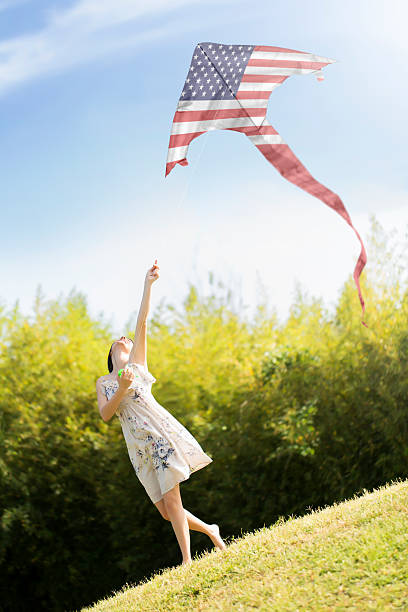 istock young woman flying an American Flag kite 491062859